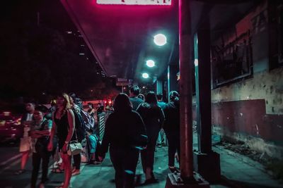 Group of people at illuminated street in city at night