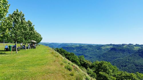 Scenic view of green landscape and mountains against clear blue sky