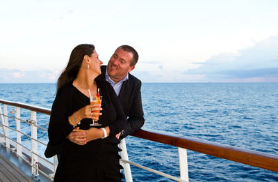 Loving mature couple standing in ship on sea during sunset