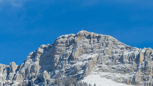 Low angle view of snowcapped mountain against blue sky