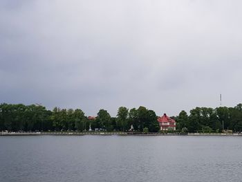 View of trees by river against sky