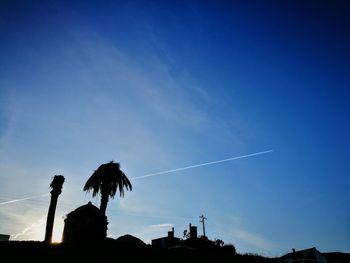 Low angle view of silhouette vapor trails in sky