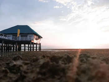 Built structure on beach against sky during sunset