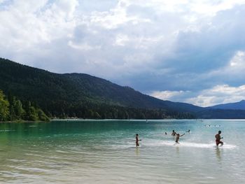 People on lake against mountain range