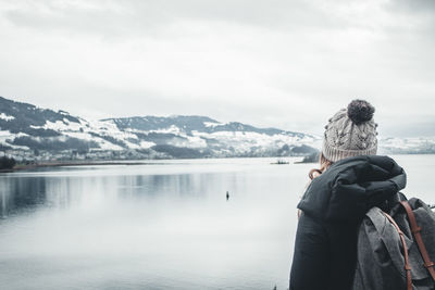 Rear view of person looking at snowcapped mountain against sky