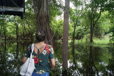 Woman standing by trees in forest