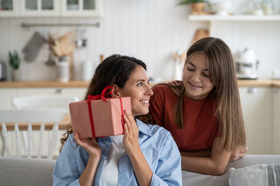 Portrait of young woman using mobile phone while sitting on sofa at home