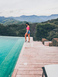 Full length of woman jumping in swimming pool against sky