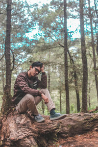 Young couple sitting on tree trunk in forest