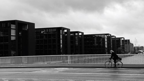 Man on bicycle in city against sky