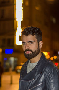 Portrait of young man standing in city at night