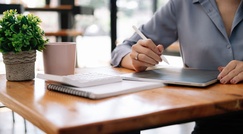 Midsection of man using laptop on table