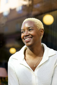 Happy owner smiling while looking away against store