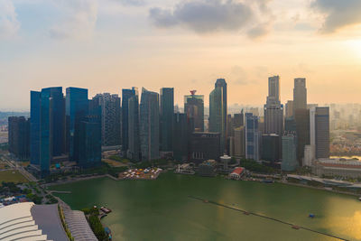 Modern buildings by swimming pool against sky during sunset