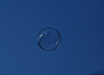Low angle view of bubbles against blue sky