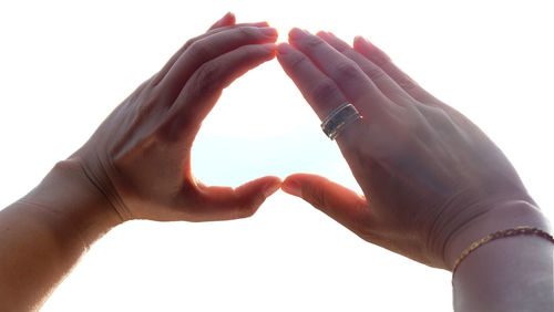 Close-up of hand holding heart shape against white background