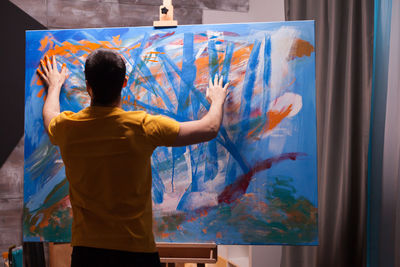 Rear view of man painting at home