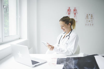 Smiling doctor using digital tablet at clinic