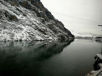Scenic view of lake by snowcapped mountain against sky