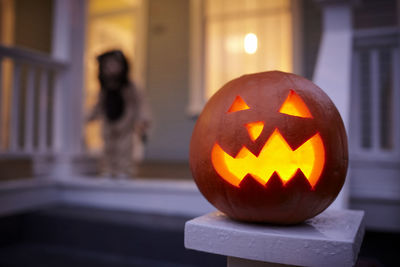 Close-up of jack o lantern with baby boy in background at dusk