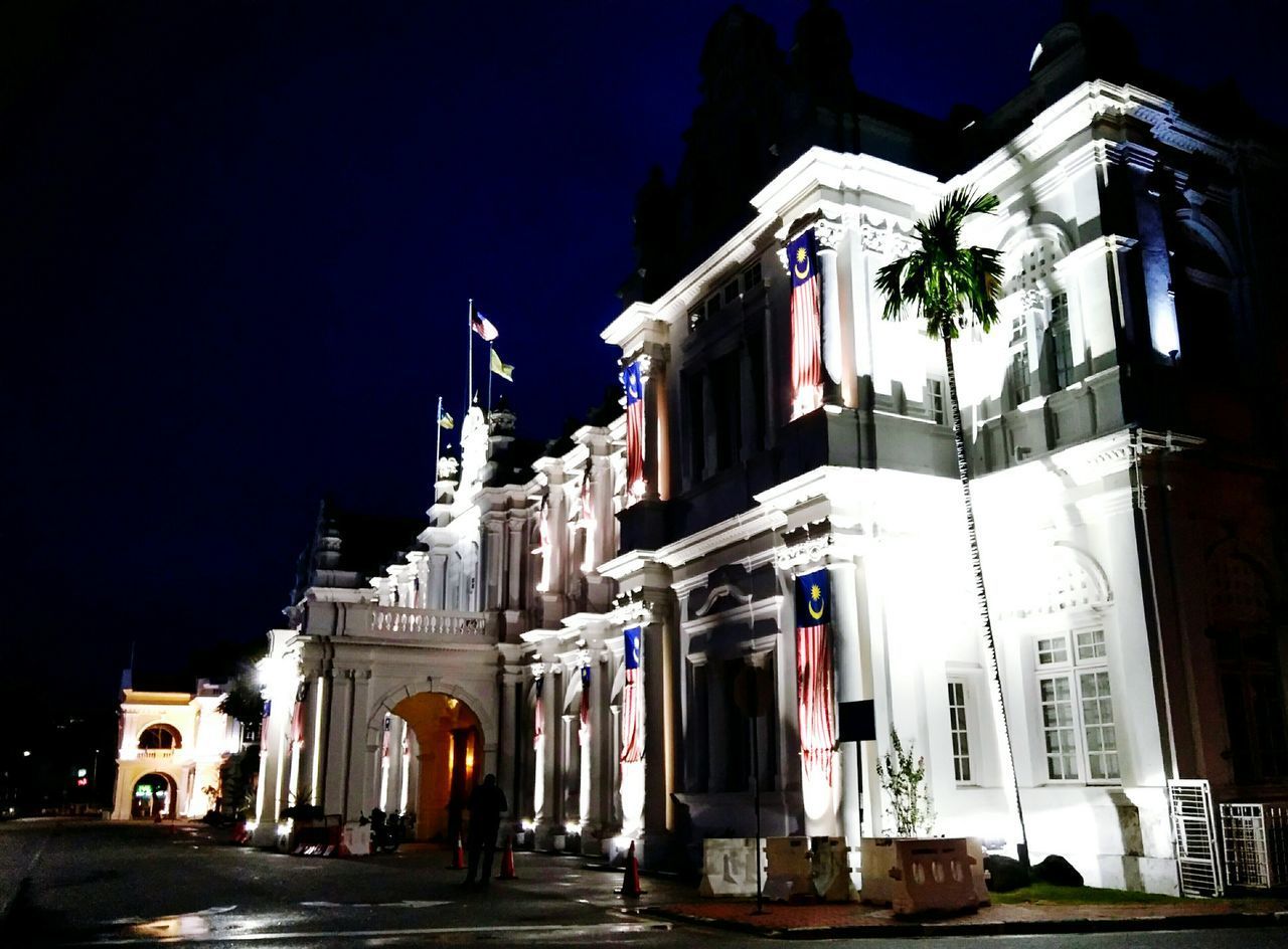 LOW ANGLE VIEW OF ILLUMINATED BUILDINGS AT NIGHT