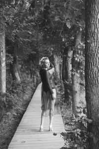 Rear view of woman standing on footpath in forest
