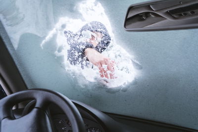 Man removing snow from car windshield