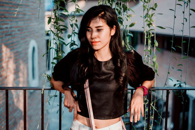 Portrait of beautiful woman standing against railing