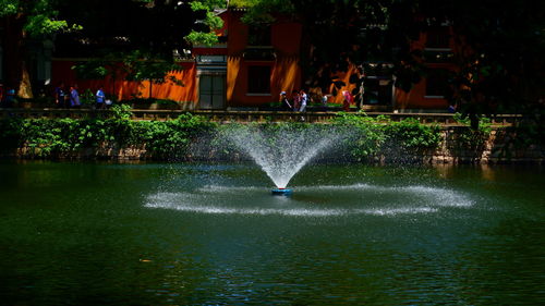 Scenic view of lake against trees in city