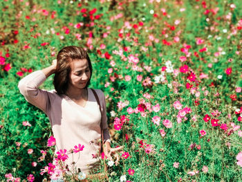 Portrait of young woman standing amidst plants