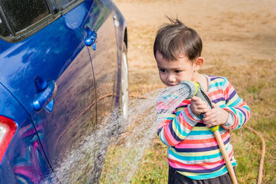 Portrait of cute boy washing car outdoors