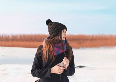 Woman wearing hat standing on snow covered land