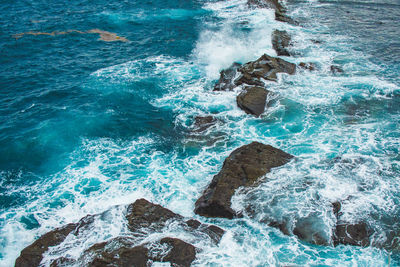 High angle view of waves splashing on rocks