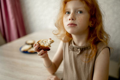 Redhead girl eating cheesecake at table