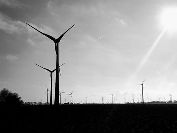 Wind turbines on field against sky