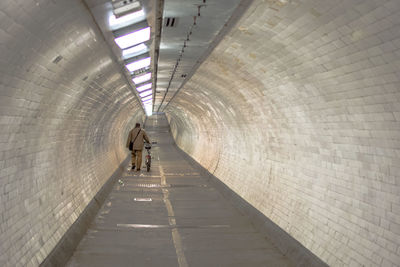 Rear view of man walking in tunnel