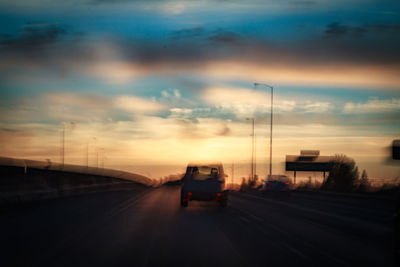 Car on highway against sky at sunset