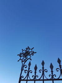 Low angle view of weather vane against clear blue sky