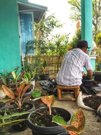 Man and woman sitting by potted plants in yard