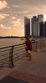 Rear view of woman standing by railing against buildings