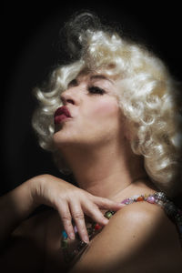 Close-up portrait of woman smoking over black background