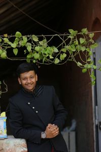 Portrait of young man standing against plants