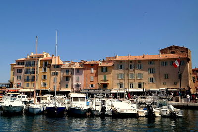 Boats moored at lake against buildings