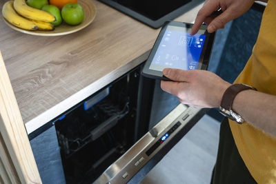 Man operating oven through digital tablet in kitchen