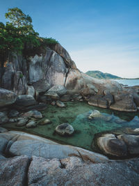 Rock formation on shore against sky