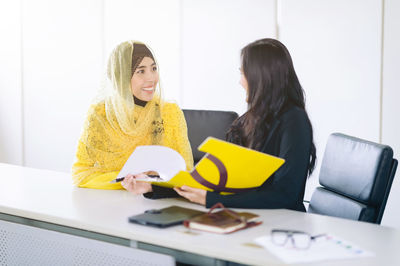 Smiling businesswomen sitting at desk in office