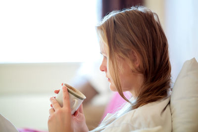 Close-up of woman holding coffee cup at home