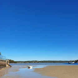 Scenic view of beach against clear blue sky