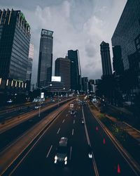 Vehicles on road amidst buildings in city against sky