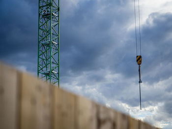Low angle view of construction crane against dramatic cloudy sky